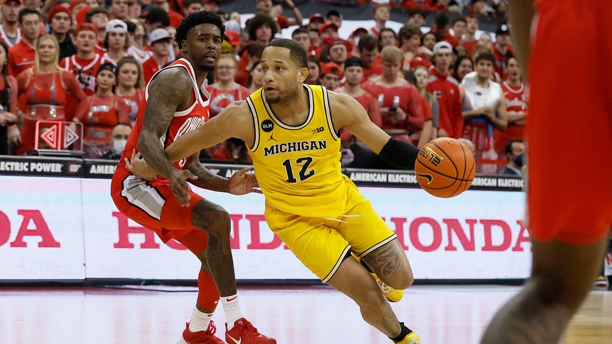 Michigan's DeVante Jones, right, dribbles up the court as Ohio State's Jamari Wheeler defends during the first half of an NCAA college basketball game, Sunday, March 6, 2022, in Columbus, Ohio.