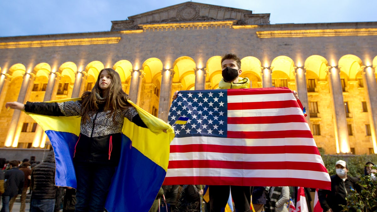 Demonstrators hold Ukrainian and U.S. national flags in front of the Georgian Parliament during an action against Russia's attack on Ukraine in Tbilisi, Georgia, Monday, March. 7, 2022. (AP Photo/Shakh Aivazov)