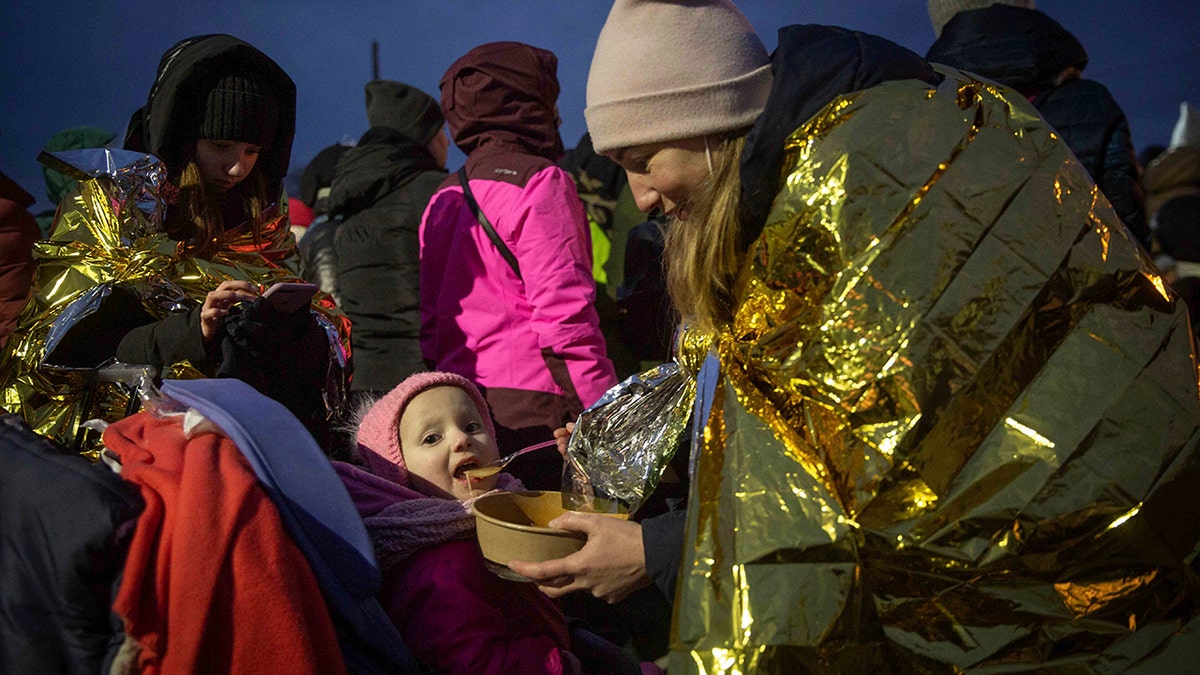 A woman feeds her daughter after fleeing Ukraine and arriving at the border crossing in Medyka, Poland, Monday, March 7, 2022. (AP Photo/Visar Kryeziu)