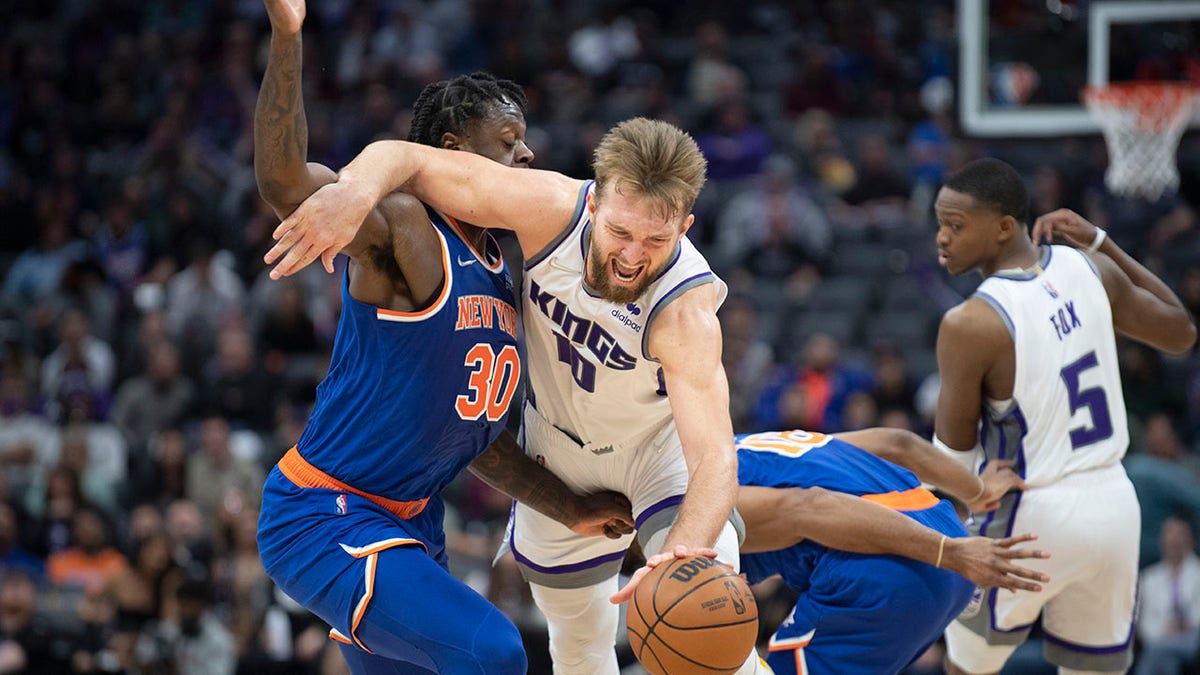 Sacramento Kings forward Domantas Sabonis (10) is fouled by New York Knicks forward Julius Randle (30) in the second half of an NBA basketball game in Sacramento, Calif., Monday, March 7, 2022. The Knicks won 131-115.