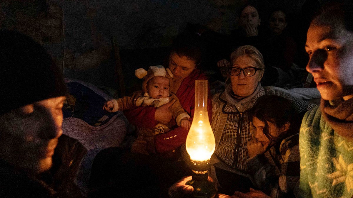 People sit around a lamp in a bomb shelter in Mariupol, Ukraine, Sunday, March 6, 2022. 