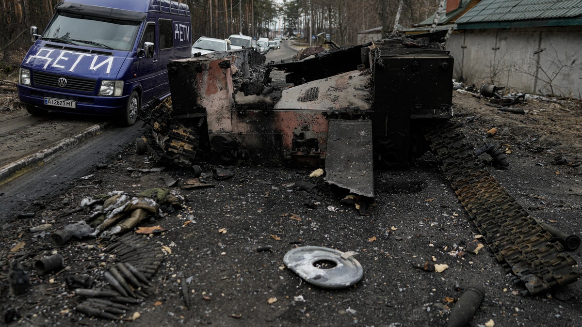 A van with the word "Children" written on it drives past a destroyed Russian tank as a convoy of vehicles evacuating civilians, leaves Irpin, on the outskirts of Kyiv, Ukraine, Wednesday, March 9, 2022. A Russian airstrike devastated a maternity hospital Wednesday in the besieged port city of Mariupol amid growing warnings from the West that Moscow's invasion is about to take a more brutal and indiscriminate turn. 