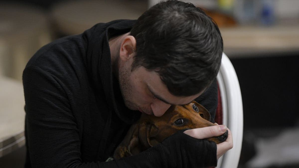 Man hugs dog in Ukraine refugee shelter
