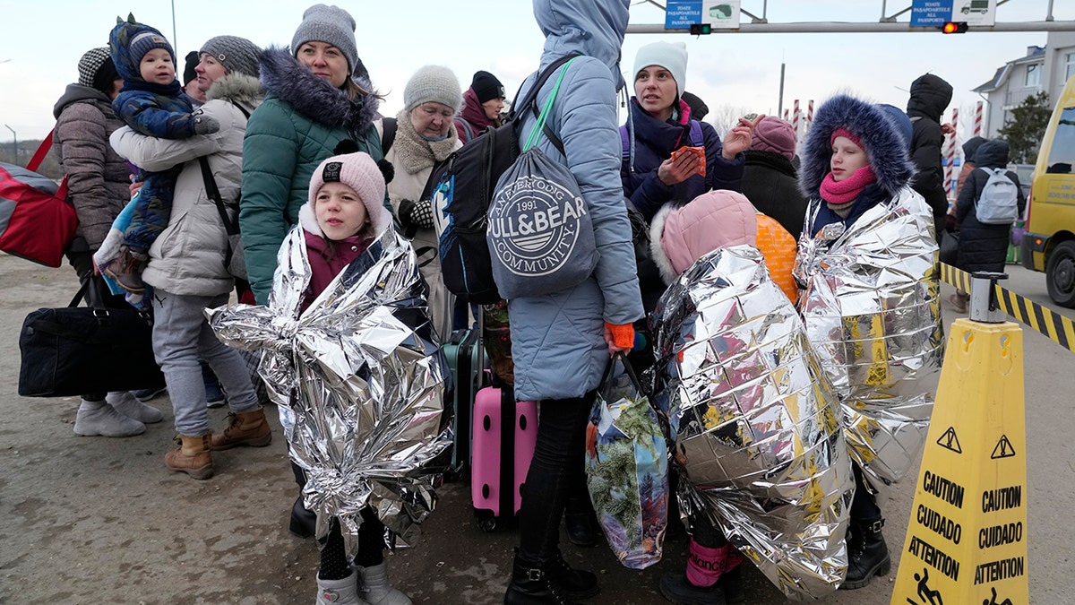 Refugees stand in a group after fleeing the war from neighboring Ukraine at the border crossing in Palanca, Moldova, Thursday, March 10, 2022.