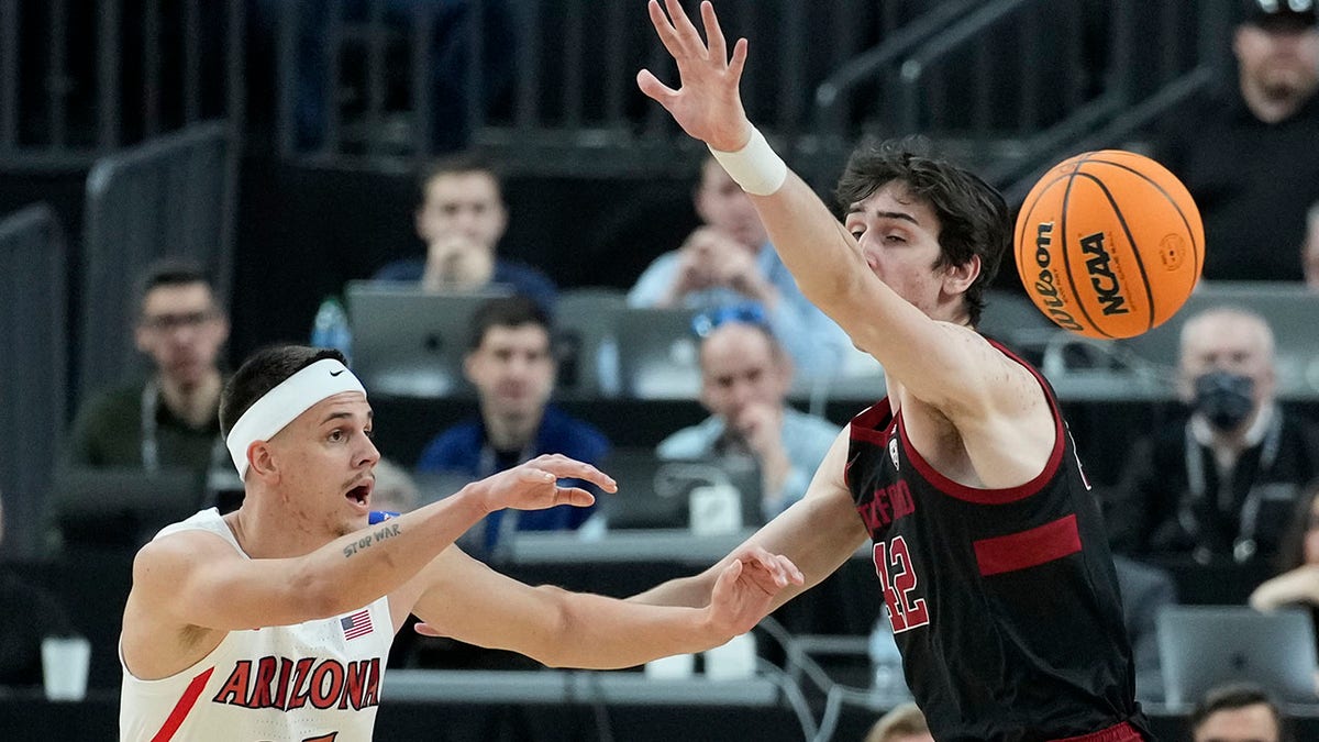 Arizona's Kerr Kriisa (25) passes around Stanford's Maxime Raynaud (42) during the first half of an NCAA college basketball game in the quarterfinal round of the Pac-12 tournament Thursday, March 10, 2022, in Las Vegas.