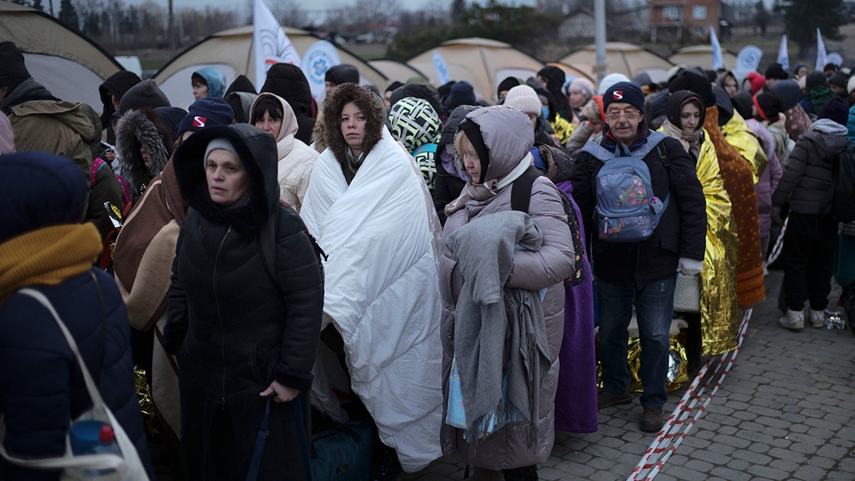 Refugees wait in a crowd for transportation after fleeing from the Ukraine and arriving at the border crossing in Medyka, Poland, Monday, March 7, 2022. (AP Photo/Markus Schreiber, File)