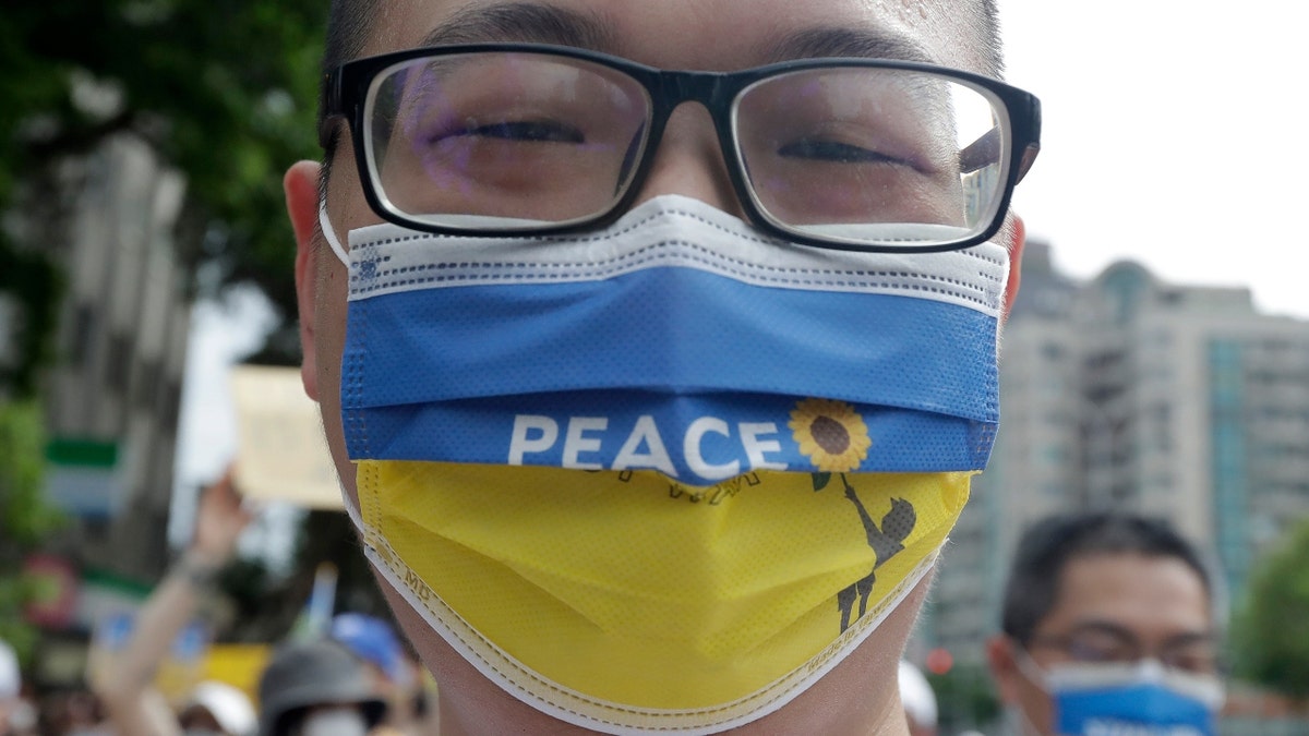 A Taiwanese man wears a Ukraine national flag-patterned mask with slogan to protest against the invasion of Russia in solidarity with the Ukrainian people during a march in Taipei, Taiwan, Sunday, March 13, 2022. (AP Photo/Chiang Ying-ying)
