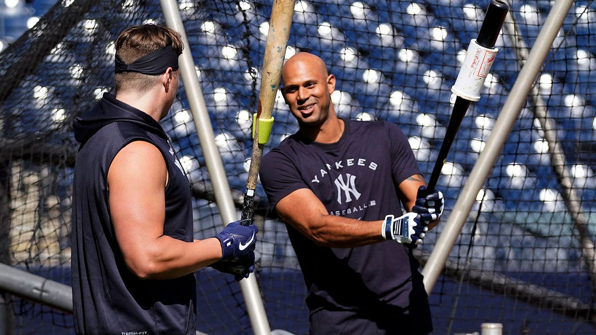 New York Yankees infielder Luke Voit, left, and outfielder Aaron Hicks talk outside the batting cage during a spring training baseball workout, Sunday, March 13, 2022, in Tampa, Fla.
