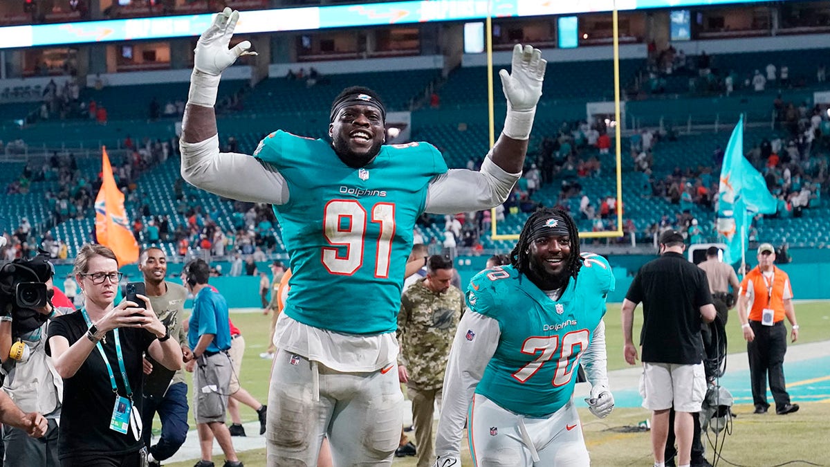 FILE - Miami Dolphins defensive end Emmanuel Ogbah (91) and nose tackle Adam Butler (70) celebrate at the end of an NFL football game against the Baltimore Ravens, Thursday, Nov. 11, 2021, in Miami Gardens, Fla. The Miami Dolphins agreed with Emmanuel Ogbah on a four-year contract and Chase Edmonds on a two-year deal on Monday, March 14, 2022.