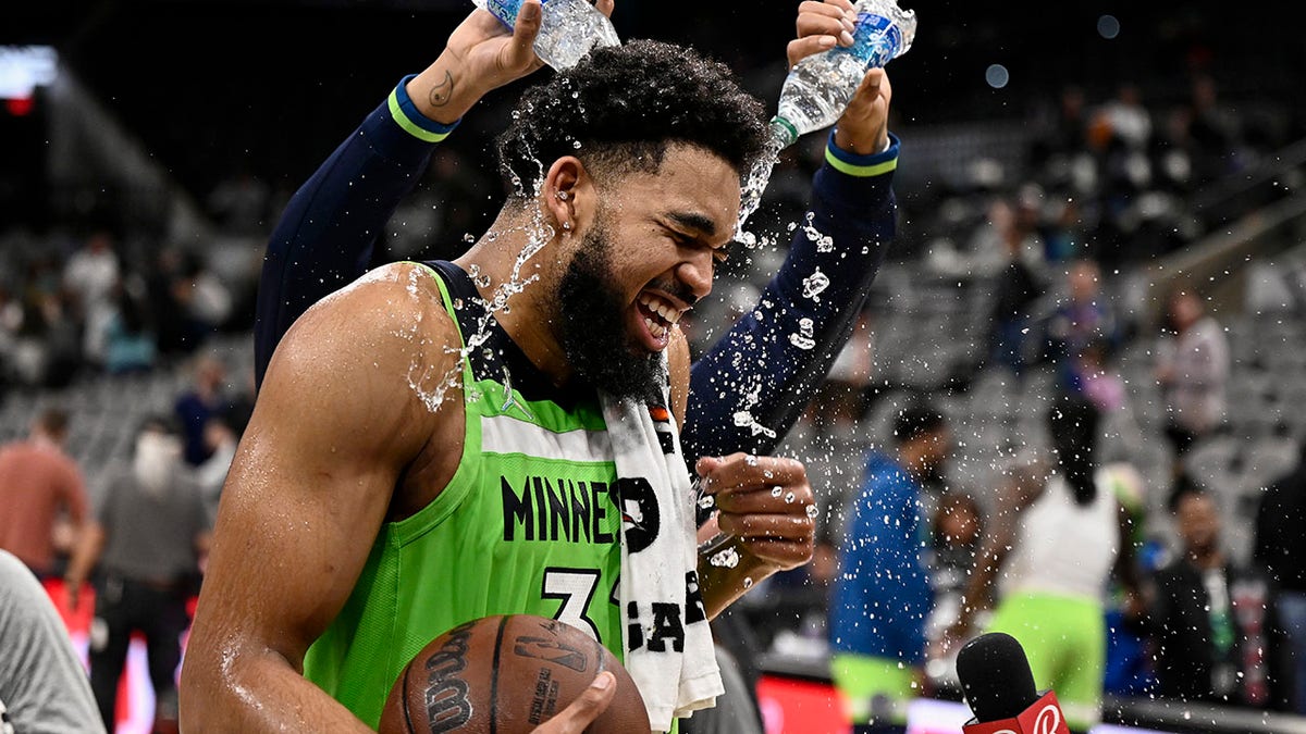 Minnesota Timberwolves center Karl-Anthony Towns is doused by teammate D'Angelo Russell, rear, after an NBA basketball game against the San Antonio Spurs on Monday, March 14, 2022, in San Antonio.