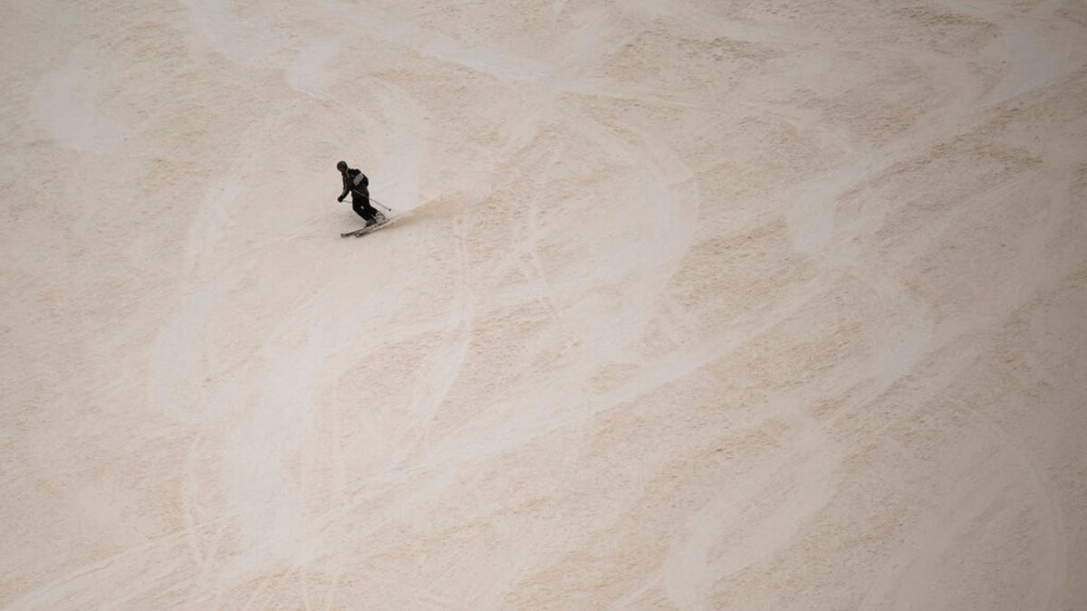 A skier descends at the Pizol ski resort on a slope partially covered with Sahara dust.