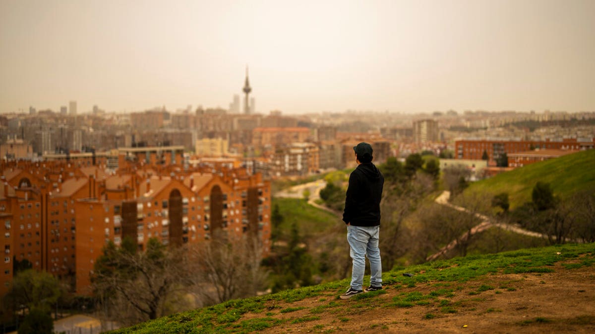 A man looks out the skyline of Madrid as storm Celia blew sand from the Sahara desert at the the Cerro del Tio Pio park in Madrid, Spain.
