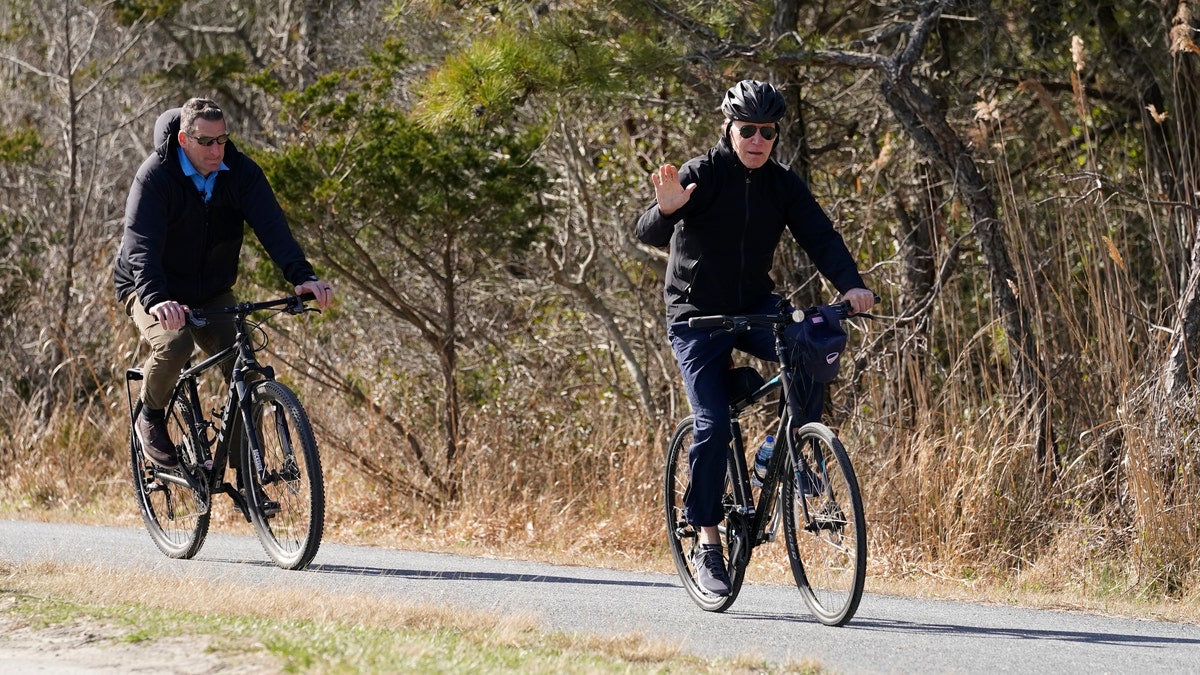 President Joe Biden waves to media as he rides a bicycle in Gordon's Pond State Park in Rehoboth Beach, Del., Sunday, March 20, 2022. (AP Photo/Carolyn Kaster)