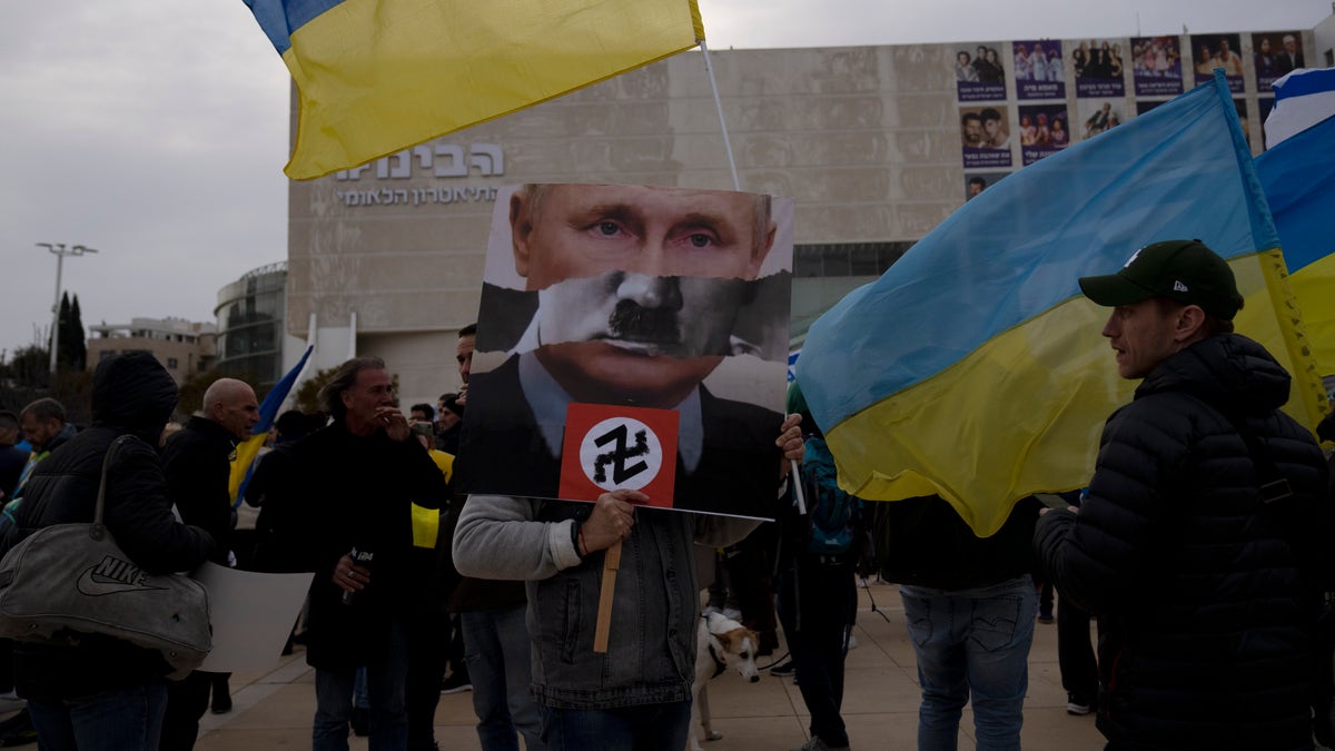 A protester in Habima Square holds a depiction of Russian President Vladimir Putin in Tel Aviv, Israel.