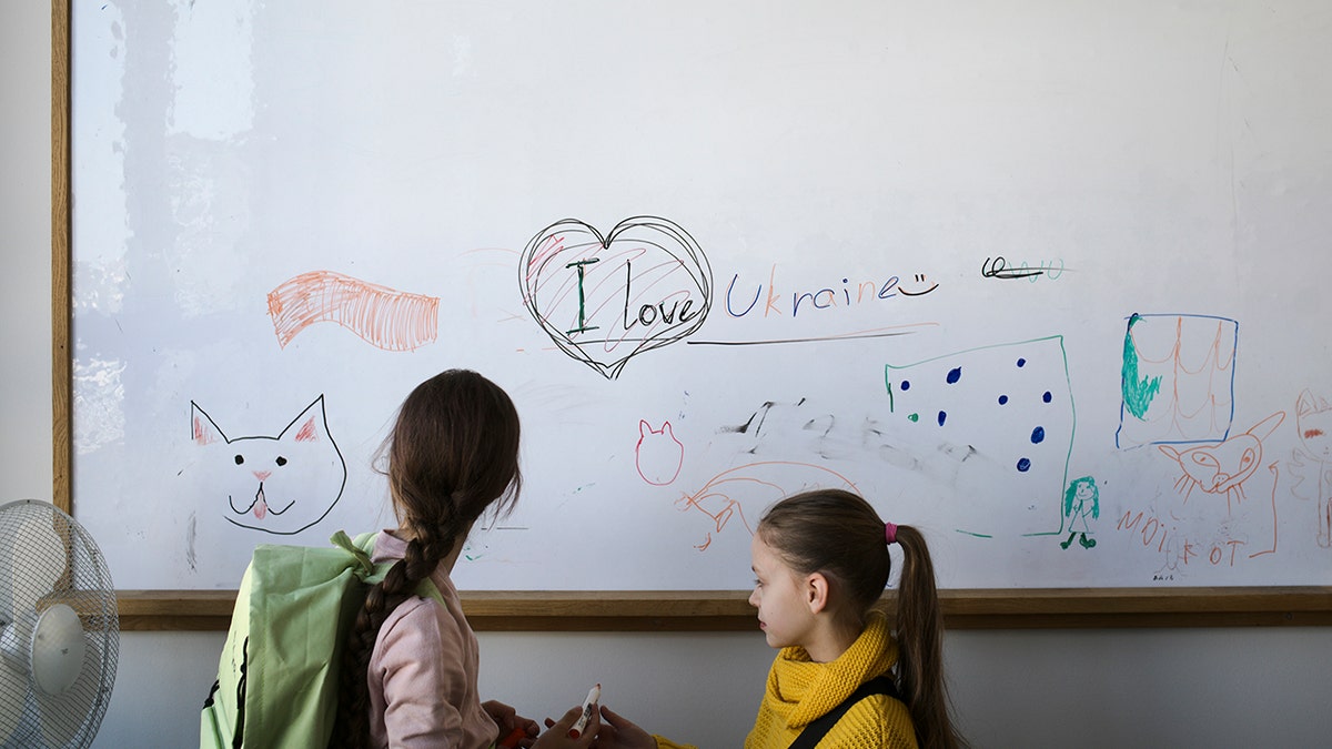 Two refugee children from the Ukraine stand in front of a white board before their classes start in Berlin, Germany, Monday, March 21, 2022. 