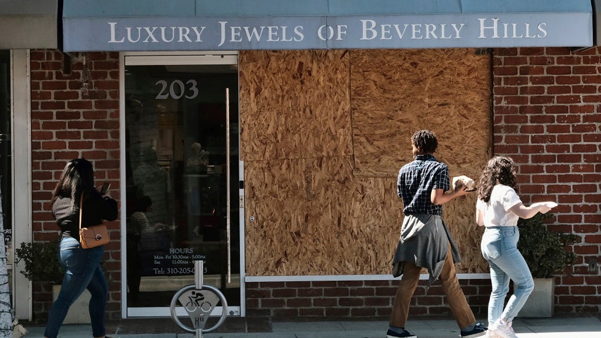 Pedestrians walk past a boarded up Luxury Jewels of Beverly Hills. Los Angeles police are warning people that wearing expensive jewelry in public could make them a target for thieves — a note of caution as robberies are up citywide. 