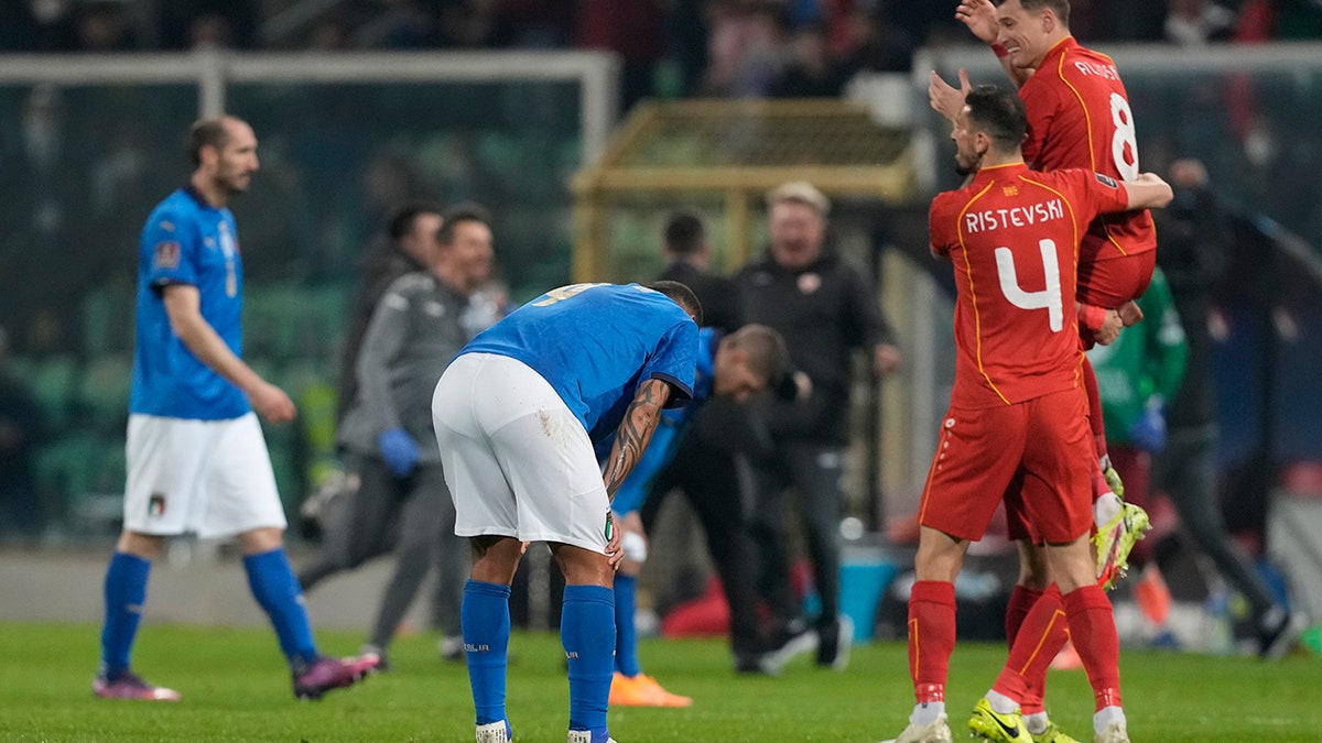 North Macedonia players celebrate as Italy players reacts after their team's elimination at the end of the World Cup qualifying play-off soccer match between Italy and North Macedonia, at Renzo Barbera stadium, in Palermo, Italy, Thursday, March 24, 2022. North Macedonia won 1-0.