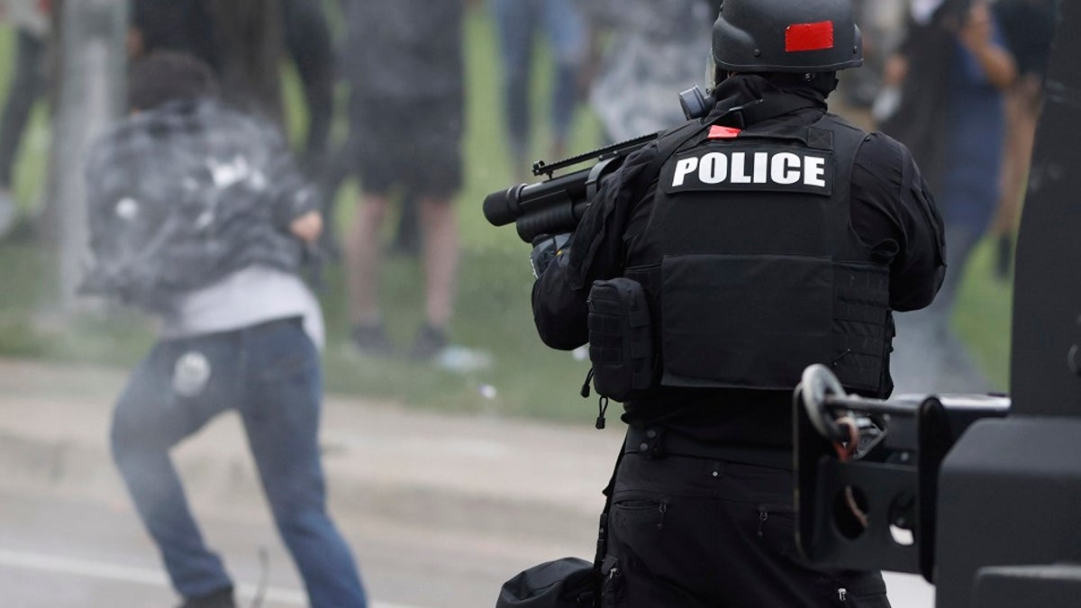 FILE - In this May 30, 2020 photo, a Denver police officer shoots a pepper ball toward a man as he retreats during a protest outside the State Capitol over the death of George Floyd in Denver.