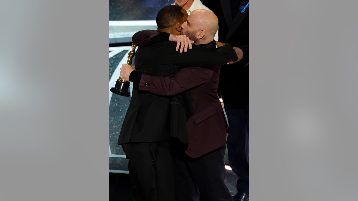 Will Smith and John Travolta hug in the audience as Will Smith is announced the winner of the award for best performance by an actor in a leading role for "King Richard" at the Oscars on Sunday, March 27, 2022. (AP Photo/Chris Pizzello)