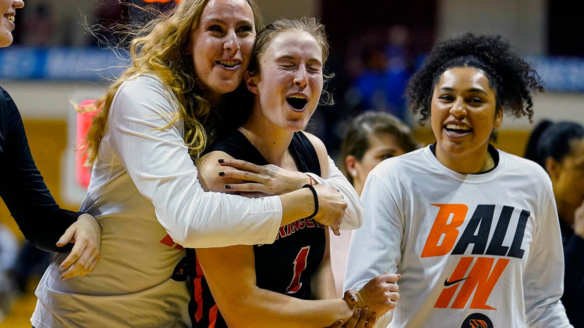 Princeton guard Abby Meyers (1) is hugged by Kira Emsbo, left, and guard Neenah Young (11) after a college basketball game in the first round of the NCAA tournament in Bloomington, Ind., Saturday, March 19, 2022. Princeton defeated Kentucky 69-62.