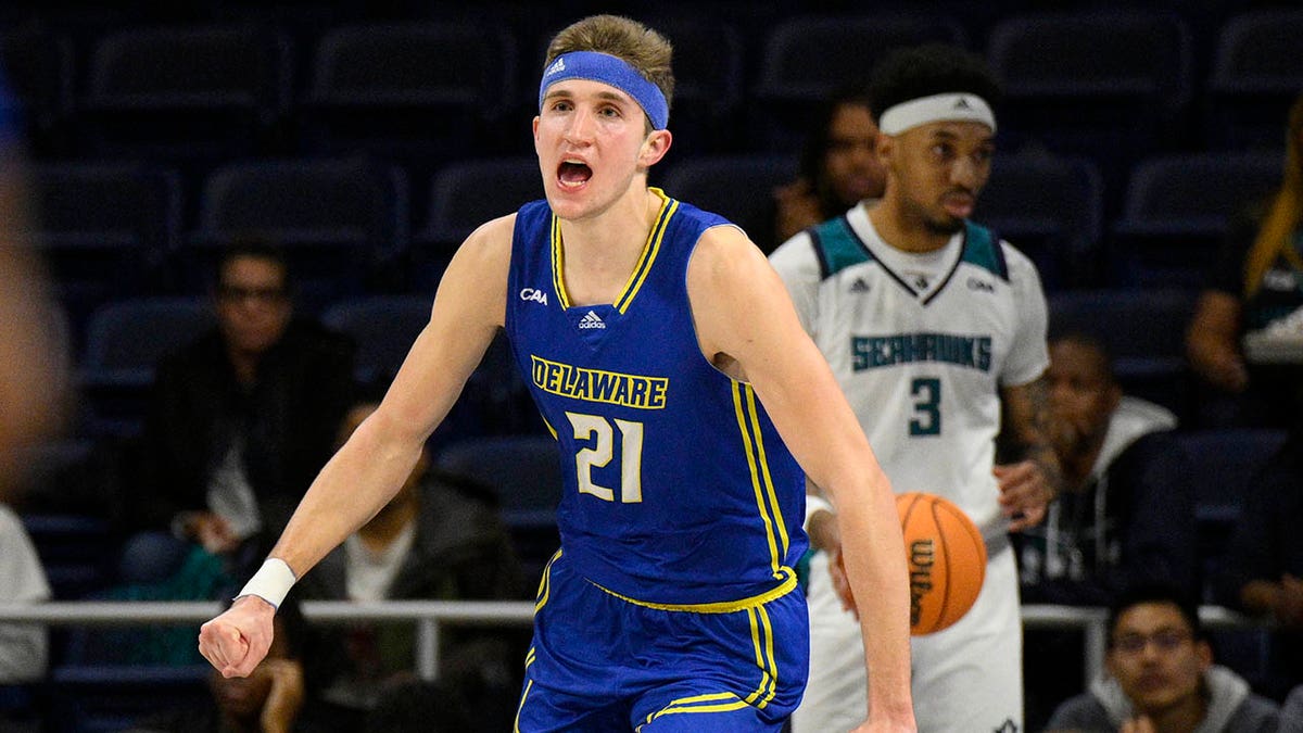Delaware forward Andrew Carr (21) reacts after his dunk during the first half of an NCAA college basketball game in the championship of the Colonial Athletic Association conference tournament, Tuesday, March 8, 2022, in Washington. UNC Wilmington guard James Baker is at back.
