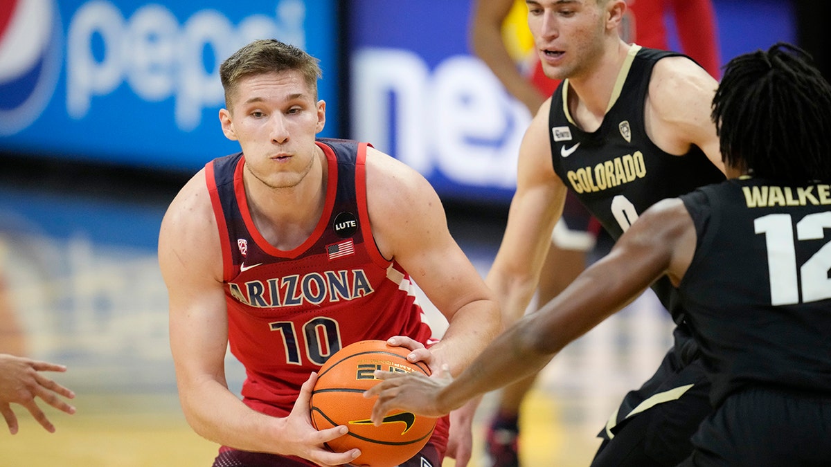 Arizona forward Azuolas Tubelis, left, drives the lane as Colorado guard Luke O'Brien, center, and forward Jabari Walker, right, defend in the first half of an NCAA college basketball game Saturday, Feb. 26, 2022, in Boulder, Colo.