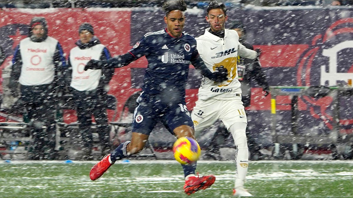 New England Revolution midfielder Brandon Bye (15) and Pumas defender Jeronimo Rodriguez (16) vie for the ball in the snow during the first half of a CONCACAF Champions League soccer match Wednesday, March 9, 2022, in Foxborough, Mass.