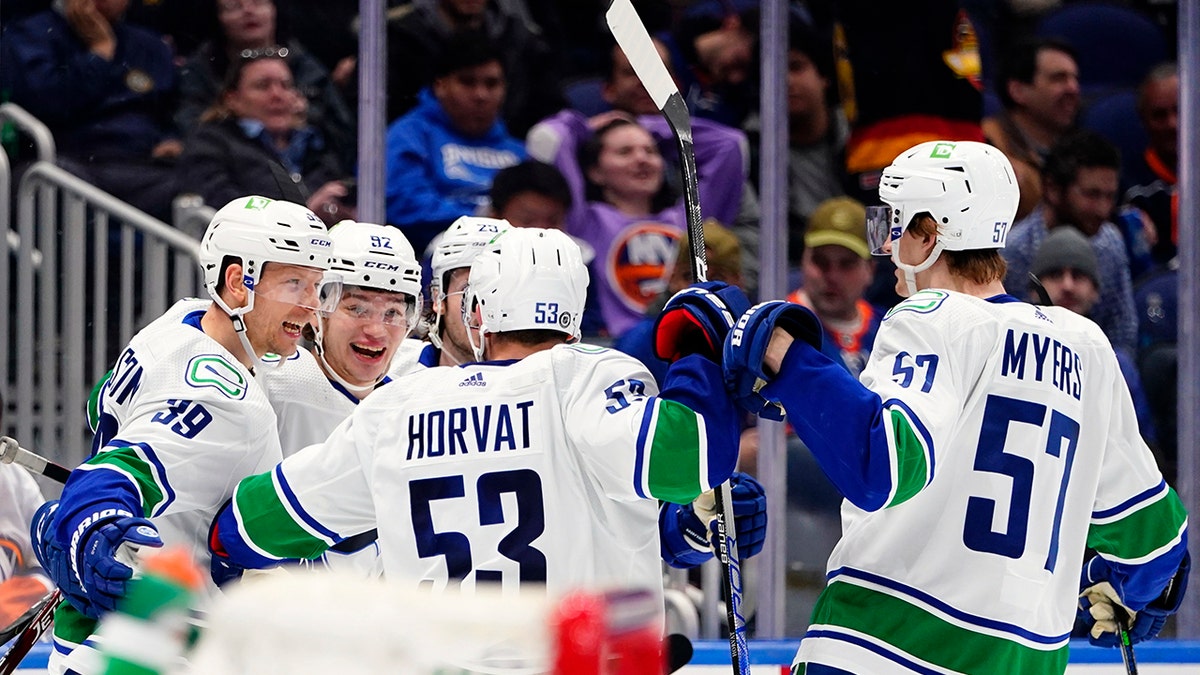 Vancouver Canucks' Vasily Podkolzin (92) celebrates with teammates Oliver Ekman-Larsson (23), Alex Chiasson (39), Bo Horvat (53) and Tyler Myers (57) after scoring a goal during the third period of an NHL hockey game against the New York Islanders, Thursday, March 3, 2022, in Elmont, N.Y.