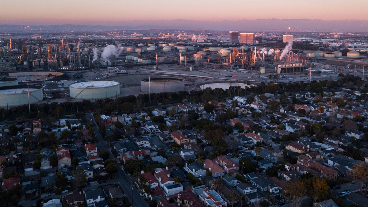 An aerial image taken on Jan. 24, 2022 shows storage tanks at the Chevron Products Company El Segundo Refinery adjacent to homes at sunset in Manhattan Beach, California. (Photo by PATRICK T. FALLON/AFP via Getty Images)