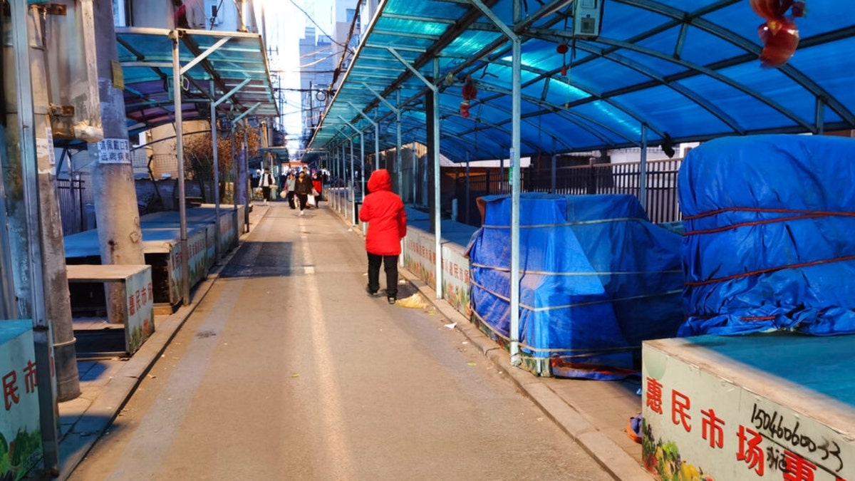 People walk through a closed market in Changchun in northeastern China's Jilin Province, Friday, March 11, 2022. China on Friday ordered a lockdown of the 9 million residents of the northeastern city of Changchun amid a new spike in COVID-19 cases in the area attributed to the highly contagious omicron variant.