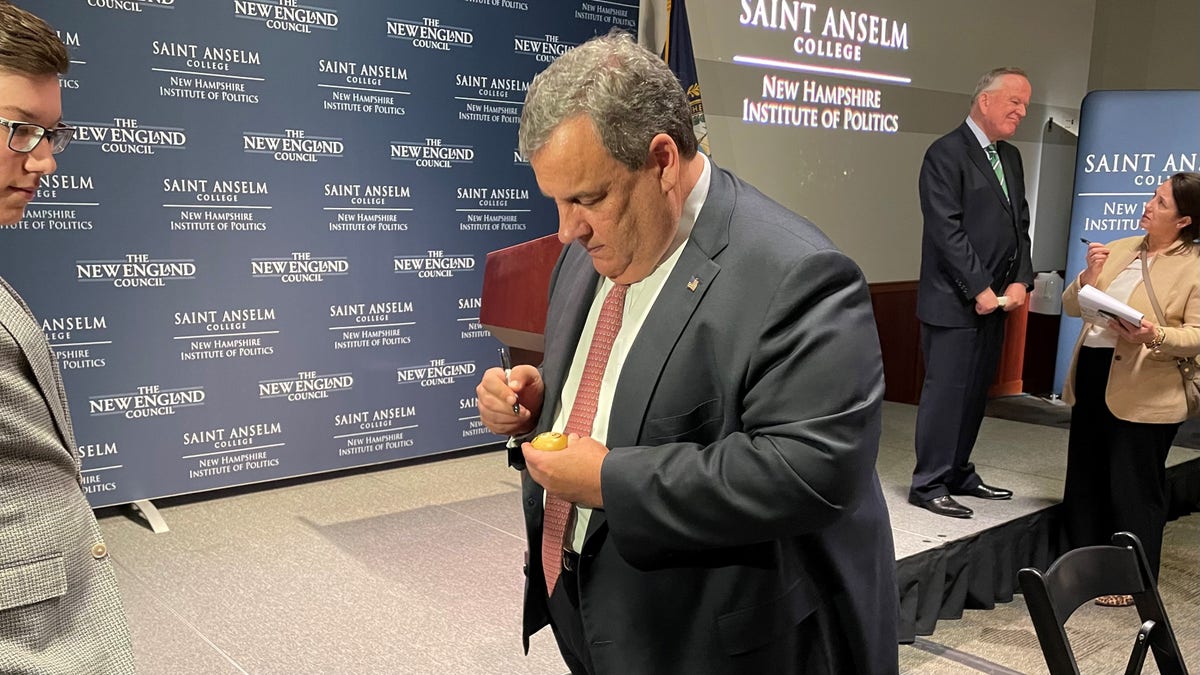 Former New Jersey Gov. Chris Christie signs the iconic wooden eggs after speaking at 'Politics and Eggs' at the New Hampshire Institute of Politics at Saint Anselm College, on March 21, 2022 in Goffstown, N.H.