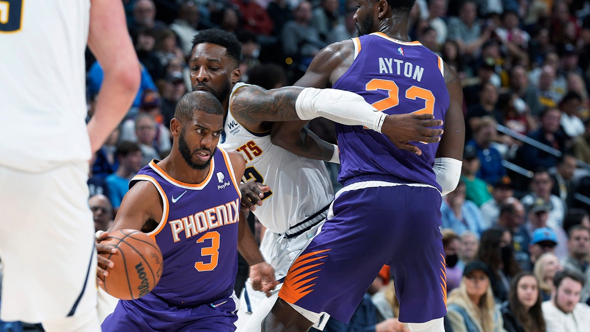 Phoenix Suns guard Chris Paul, left, drives past Denver Nuggets forward Jeff Green, center, who is screened by Suns center Deandre Ayton during the second half of an NBA basketball game Thursday, March 24, 2022, in Denver.