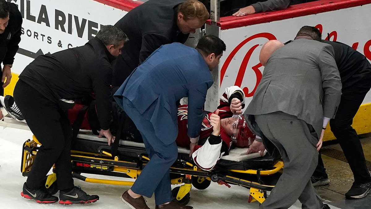 Arizona Coyotes' Clayton Keller (9) gives a thumbs-up as he is removed on a stretcher after colliding against the boards during the third period of the team's NHL hockey game against the San Jose Sharks, Wednesday, March 30, 2022, in Glendale, Arizona.