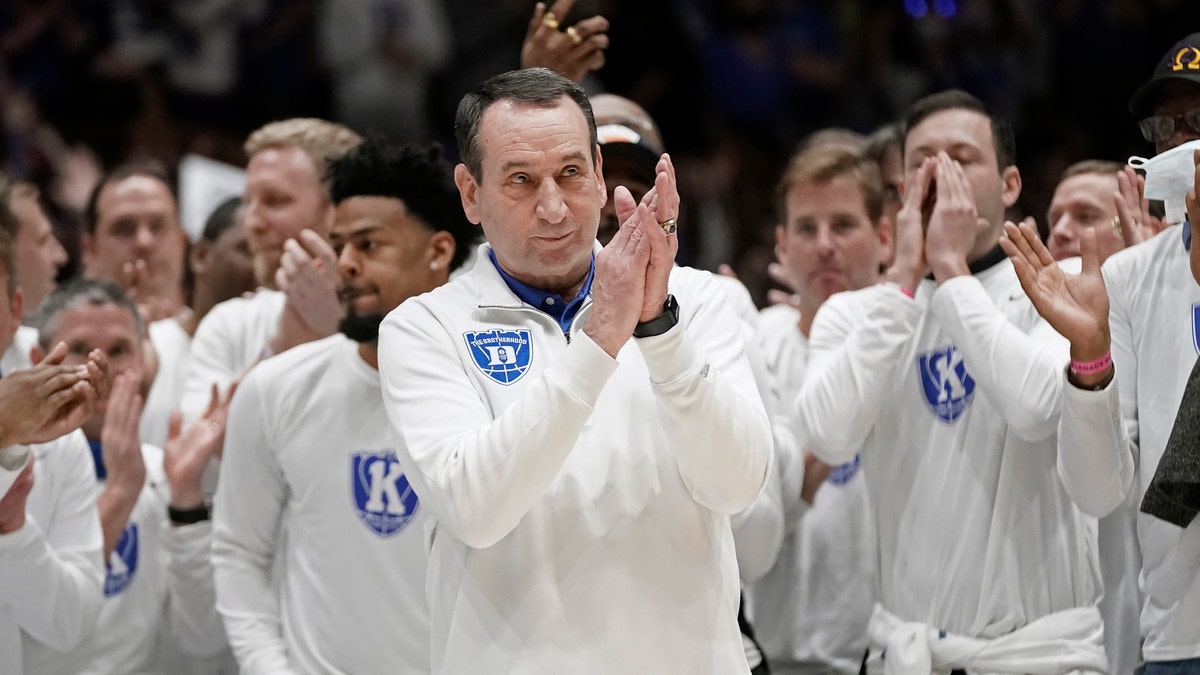 Surrounded by former players, Duke coach Mike Krzyzewski applauds while being recognized prior to the team's NCAA college basketball game against North Carolina in Durham, N.C., Saturday, March 5, 2022. The matchup is Krzyzewski's final game at Cameron Indoor Stadium. (AP Photo/Gerry Broome)