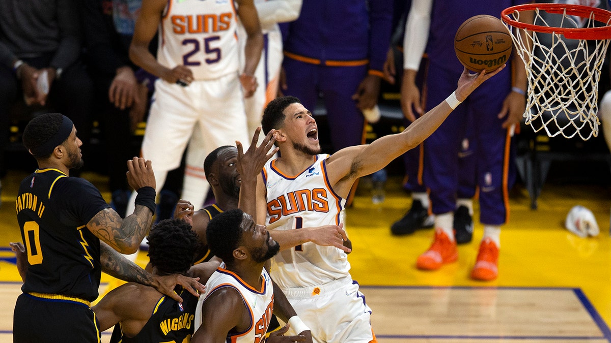 Phoenix Suns guard Devin Booker (1) drives to the basket through a trio of Golden State Warriors defenders during the third quarter of an NBA basketball game Wednesday, March 30, 2022, in San Francisco.