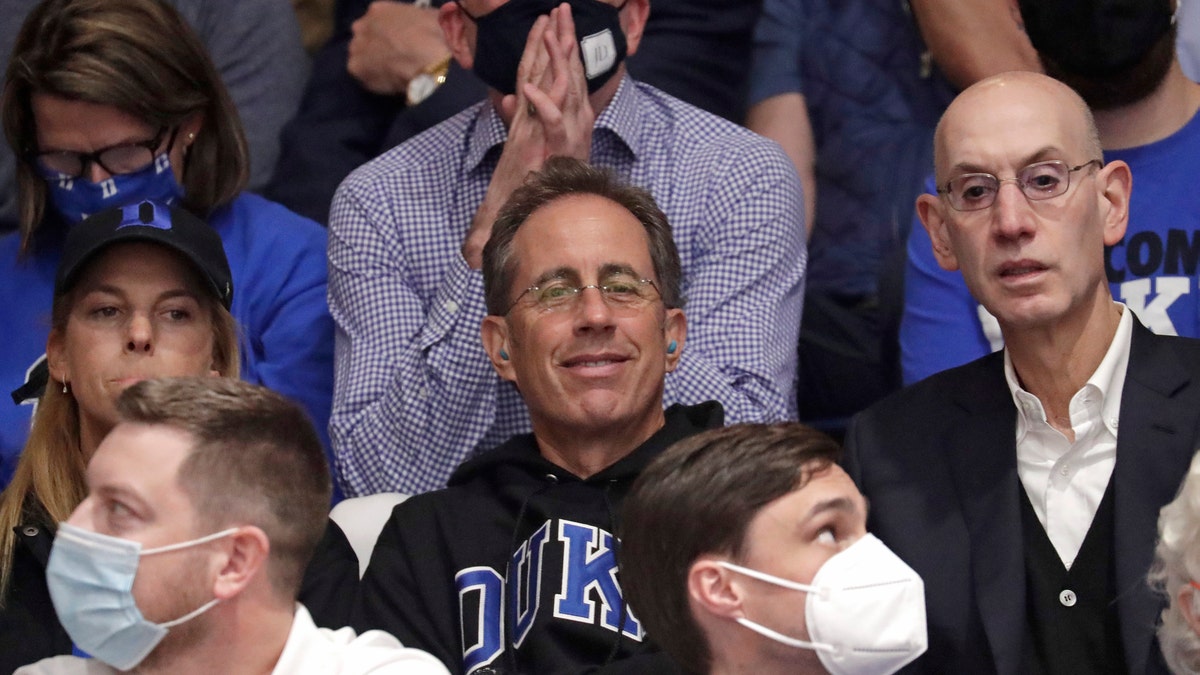 Actor and comedian Jerry Seinfeld, center, sits next to NBA Commissioner Adam Silver, right, prior to an NCAA college basketball game between Duke and North Carolina in Durham, N.C., Saturday, March 5, 2022.?