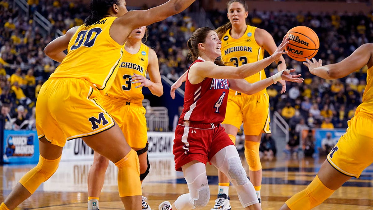 American guard Emily Fisher (4) passes as Michigan forward Naz Hillmon (00) defends during the second half of a college basketball game in the first round of the NCAA tournament, Saturday, March 19, 2022, in Ann Arbor, Mich.