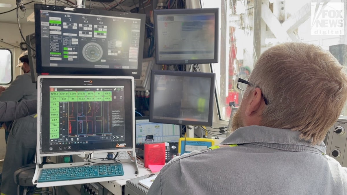 Operator observing readouts from natural gas rig on Jonah Field in Wyoming.