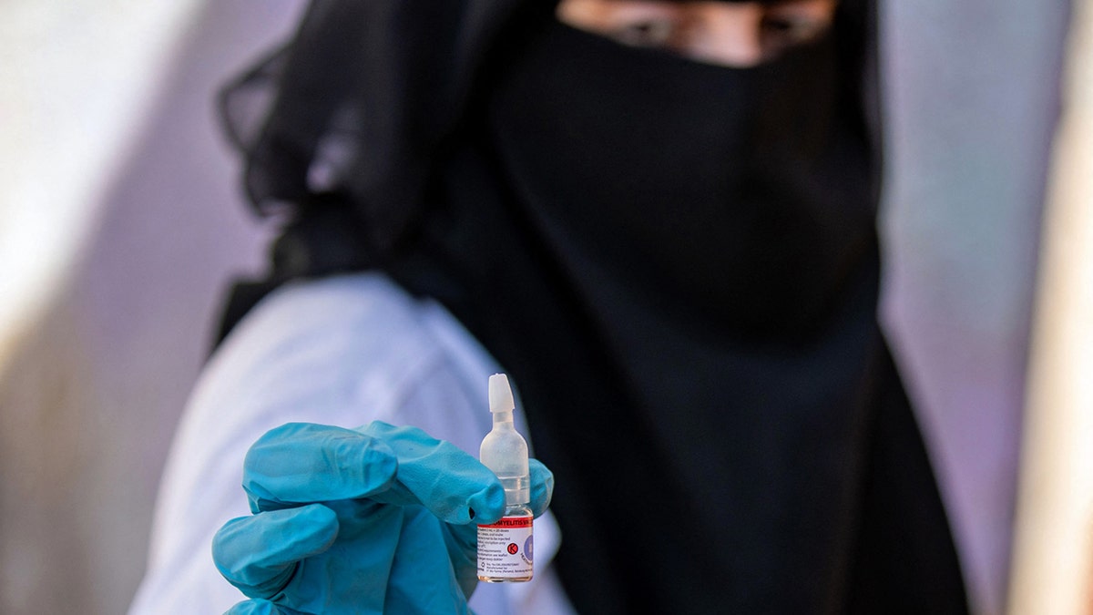 A Yemeni health worker holds a vial containing the polio vaccine during a vaccination campaign in Yemen's third city of Taez, on Feb. 19, 2022 (Photo by AHMAD AL-BASHA/AFP via Getty Images)