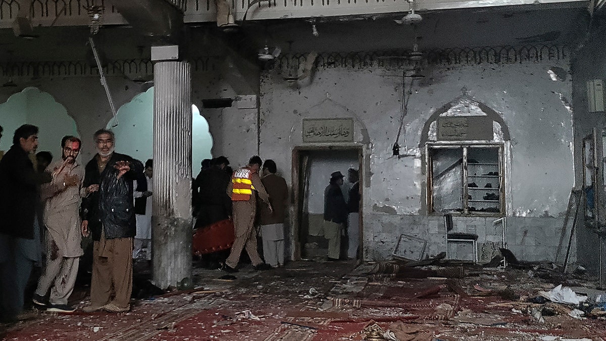 Security personnel inspect a mosque after a bomb blast in Peshawar on March 4, 2022.