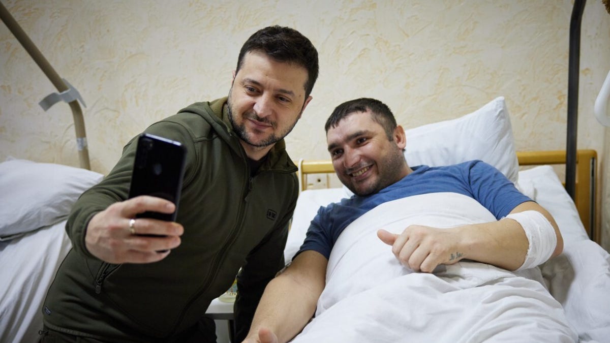 Ukrainian President Vladimir Zelenskiy takes a photo with a wounded soldier by Russian attacks on Ukraine during his hospital visit in Kyiv, Ukraine on March 13, 2022. 