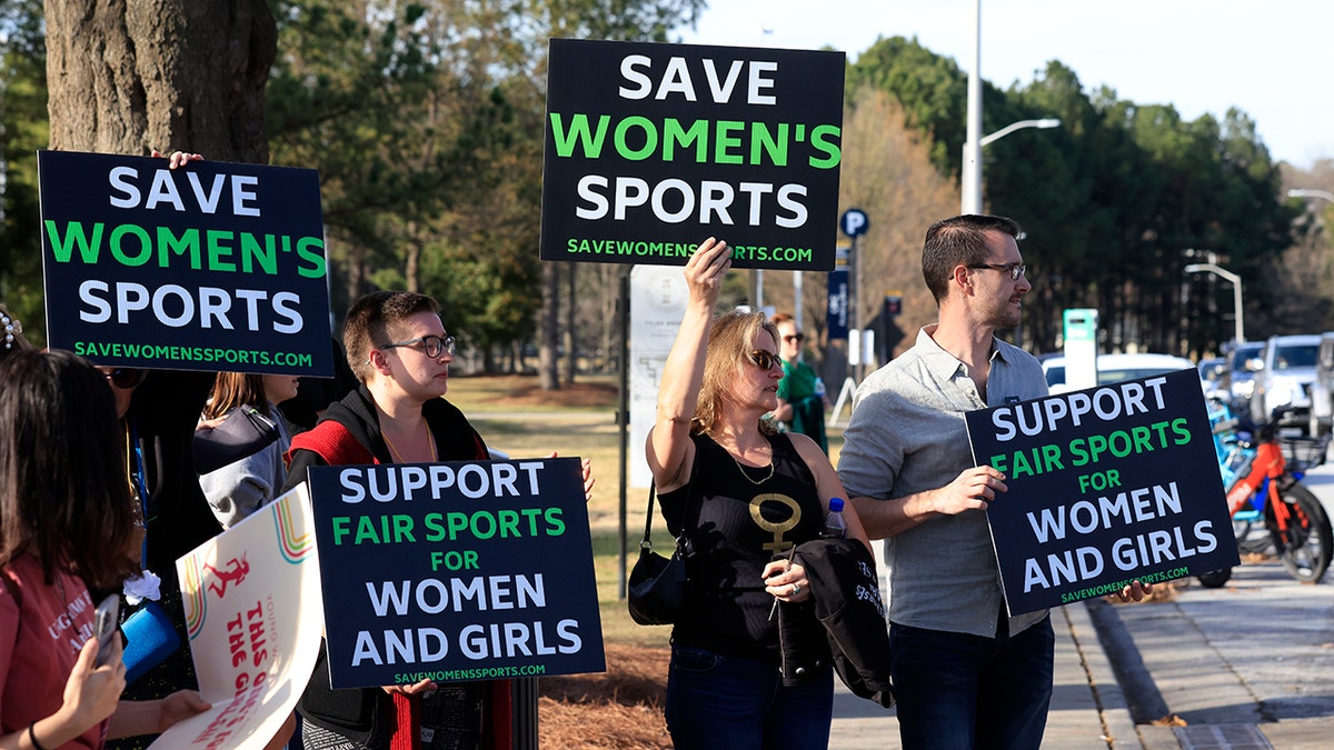 Protesters hold up signs before the 2022 NCAA Division I Women's Swimming and Diving Championship at the McAuley Aquatic Center on the campus of the Georgia Institute of Technology on March 17, 2022 in Indianapolis, Indiana.