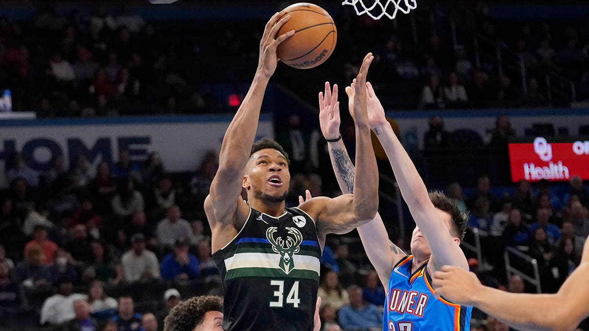 Milwaukee Bucks forward Giannis Antetokounmpo (34) goes to the basket between Oklahoma City Thunder forward Isaiah Roby, left, and guard Vit Krejci (27) in the second half of an NBA basketball game Tuesday, March 8, 2022, in Oklahoma City.