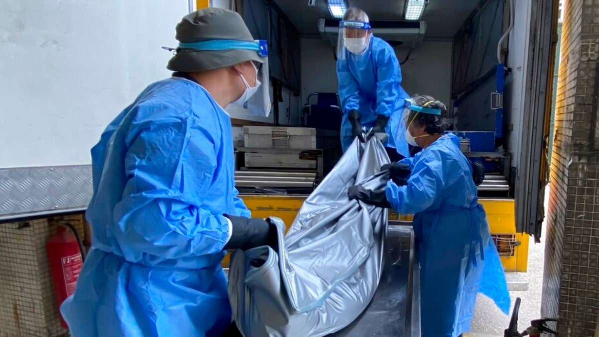Workers from the Food and Environmental Hygiene Department, move a corpse from the mortuary to the coffin van at the Queen Elizabeth Hospital in Hong Kong, Wednesday, March 2, 2022. Some hospitals in Hong Kong are currently being overloaded with possible COVID-infected patients.