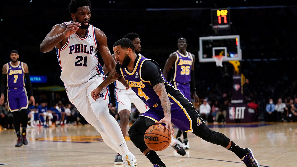 Philadelphia 76ers center Joel Embiid (21) defends against Los Angeles Lakers guard D.J. Augustin (4) during the first half of an NBA basketball game in Los Angeles, Wednesday, March 23, 2022.