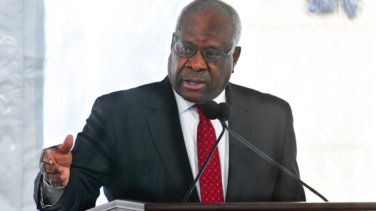 Justice Clarence Thomas in coat and tie at lectern