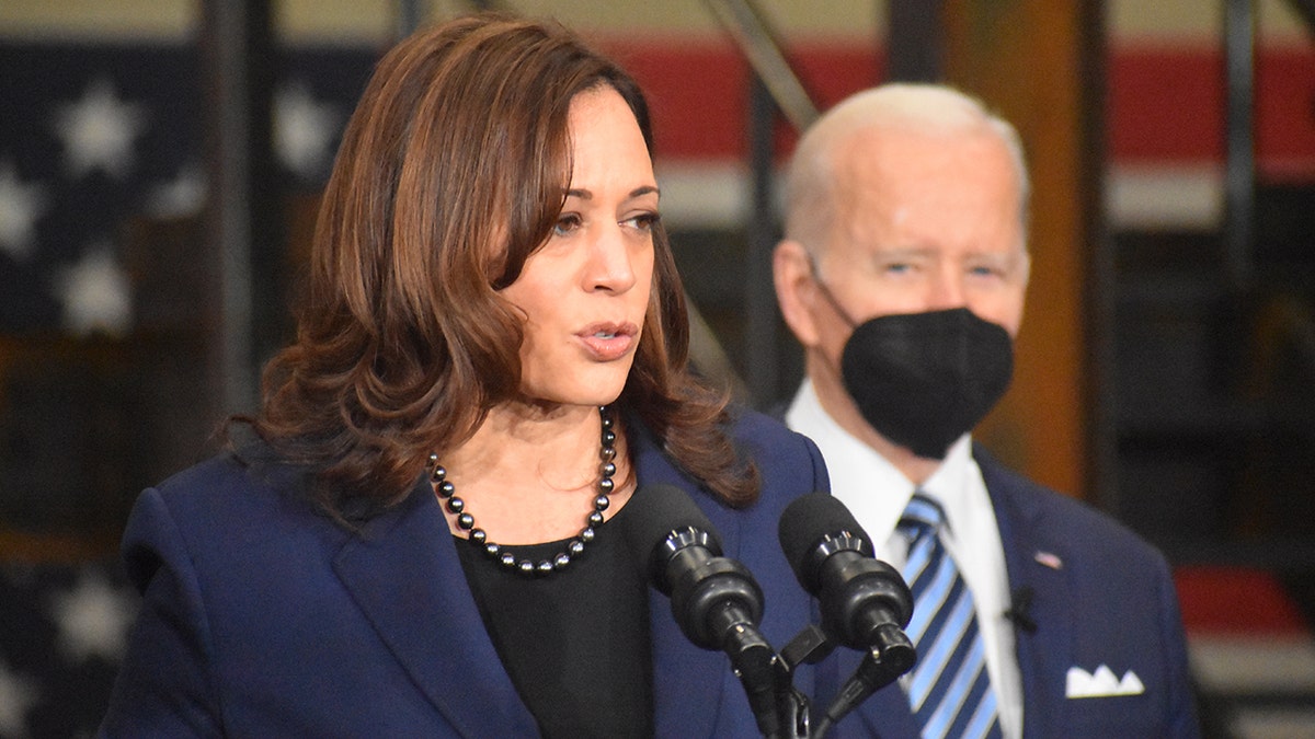 Vice President Kamala Harris speaking at podium with President Biden behind her