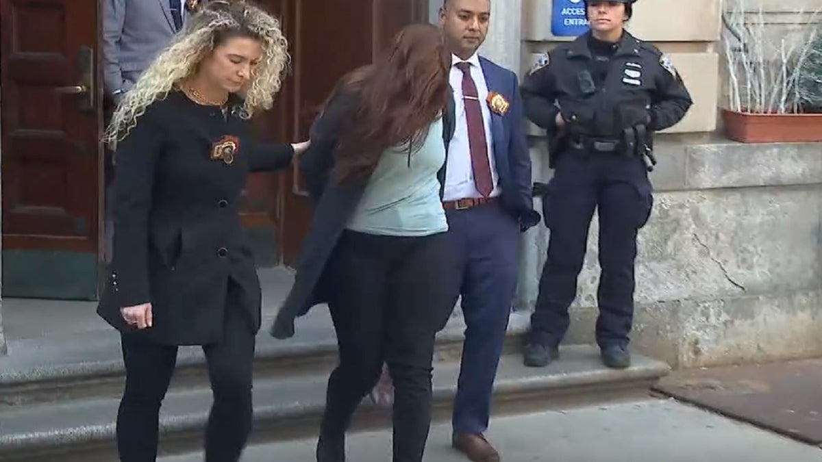 Photo shows Lauren Pazienza being led out of the NYPD's 10th Precinct on March 22, 2022. 