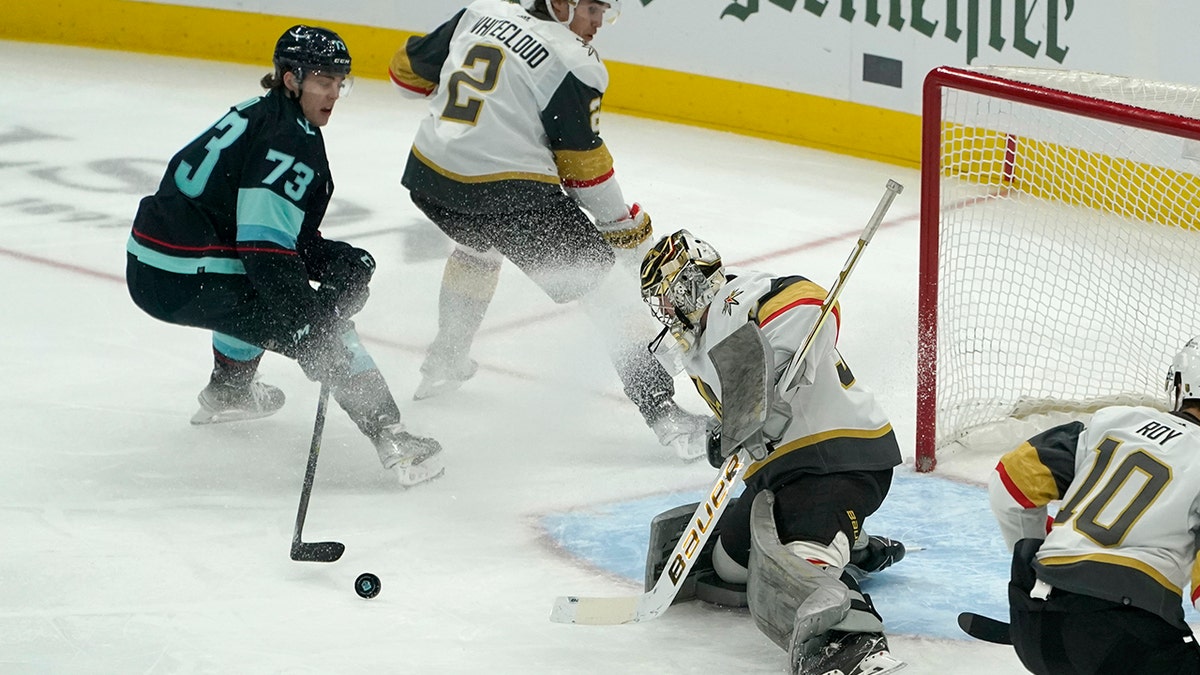 Vegas Golden Knights goaltender Logan Thompson eyes the puck after he deflected a shot by Seattle Kraken right wing Kole Lind (73) during the first period of an NHL hockey game, Wednesday, March 30, 2022, in Seattle.