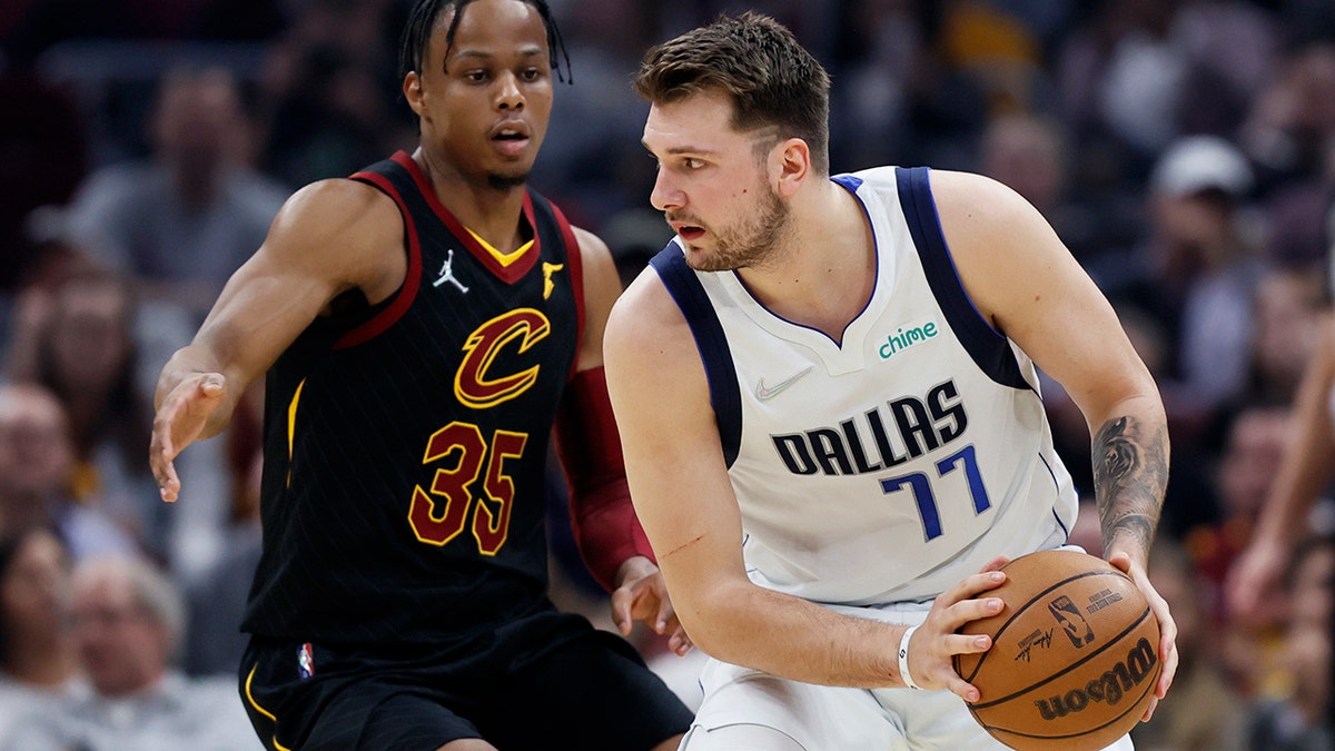 Dallas Mavericks guard Luka Doncic (77) is defended by Cleveland Cavaliers guard Isaac Okoro (35) during the first half of an NBA basketball game Wednesday, March 30, 2022, in Cleveland.